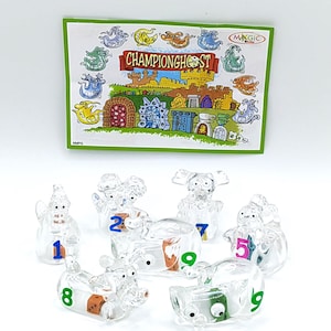Op de afbeelding: Een Championghost bordspelset met doorzichtige plastic spookfiguren genummerd van 1 tot 9. Het spel bevat een kleurrijke kaart met de titel van het spel en cartoon illustraties van geesten en een kasteel.