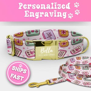 May include: A pet collar and matching leash featuring a light pink background with a repeating pattern of colorful mahjong tiles, including bamboo, flower, and dot designs. The collar has a gold-tone metal buckle engraved with the name Bella.