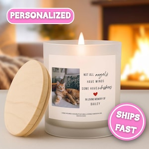 May include: A frosted glass candle with a wooden lid, featuring a label with a photograph of an orange tabby cat and the text: Not all angels have wings, some have whiskers, in loving memory of Bailey. The candle has a lit wick at the top.