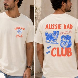 May include: Ivory t-shirt with the text "AUSSIE DAD Club" in red and blue. The back of the shirt features a blue illustration of an Australian Shepherd dog and the phrase "Life is better with Australian shepherd."