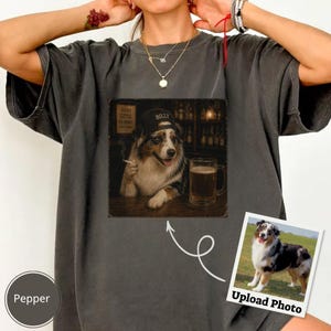 Può includere: Una t-shirt grigio antracite con la grafica di un pastore australiano che indossa un berretto da baseball nero, tiene una sigaretta e siede accanto a un boccale di birra. Una piccola foto quadrata dello stesso cane è posizionata in basso a destra.