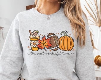 May include: A gray sweatshirt with a graphic design of a pumpkin, football, and a fall-themed coffee drink. The text "the most wonderful time" is printed below the graphic.