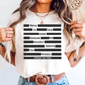 Può includere: T-shirt color crema con testo nero disposto in linee orizzontali. Il testo recita: "We're in this mess because we wouldn't believe the women. release the files."