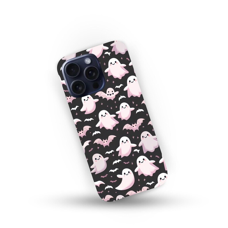 May include: A black phone case featuring a pattern of smiling pink ghosts and bats. The case has a glossy finish and a camera cutout. The design is repeated across the surface, creating a Halloween-themed accessory.