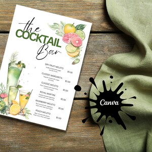 May include: A white menu with green watercolor illustrations of cocktails and fruit. The menu is titled "The Cocktail Bar" and lists various cocktails with prices. The menu is on a wooden surface with a green cloth napkin.
