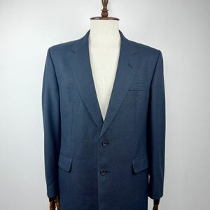 May include: A dark blue blazer with a three-button closure and a single pocket on the left side.