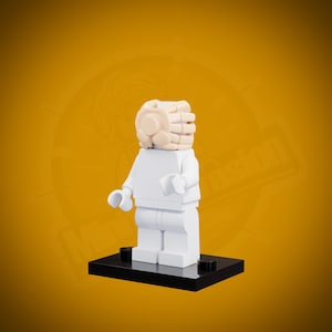 May include: White Lego minifigure with a white head and a white torso. The minifigure is standing on a black baseplate.