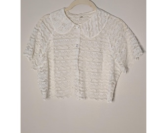 Blusa corta estilo eduardiano blanca de encaje floral con botones de perlas en la parte delantera y cuello Peter Pan.