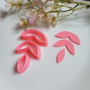 Könnte beinhalten: Rosa Plastik-Ausstecher in Blattform. Es gibt insgesamt fünf Ausstecher, vier sind übereinander gestapelt und einer ist separat.