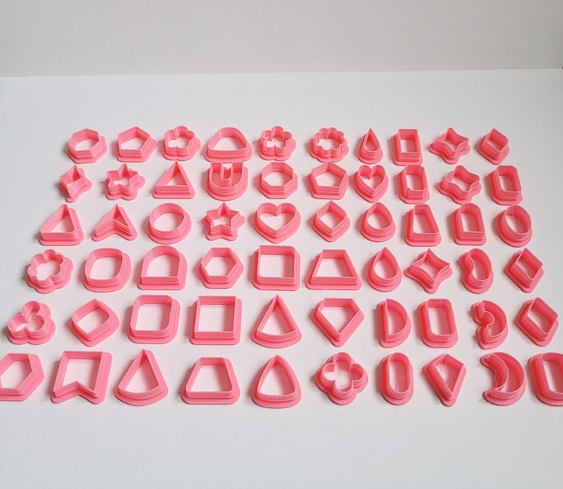 May include: A set of 48 pink plastic cookie cutters in various shapes, including stars, hearts, circles, squares, triangles, diamonds, and flowers.