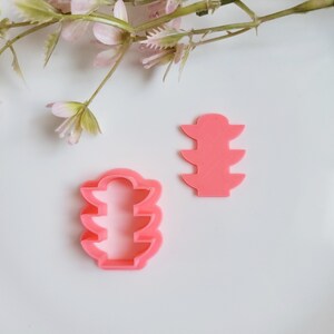 May include: Two pink plastic cookie cutters shaped like traffic lights. The cutters are on a white surface.