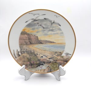 May include: A set of three ceramic mugs with a speckled, matte finish. The mugs are in shades of cream, light gray, and dark gray. Each mug has a simple, minimalist design, perfect for coffee or tea.