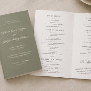 Könnte beinhalten: Ein salbeigrünes Hochzeitsprogramm mit weißem Text und einem passenden, aufgeschlagenen weißen Innenheft. Das Deckblatt zeigt die Namen Catherine Grace Higgins und Joseph Anthony Sullivan, während das Innere die Zeremonie und Liturgie auflistet.