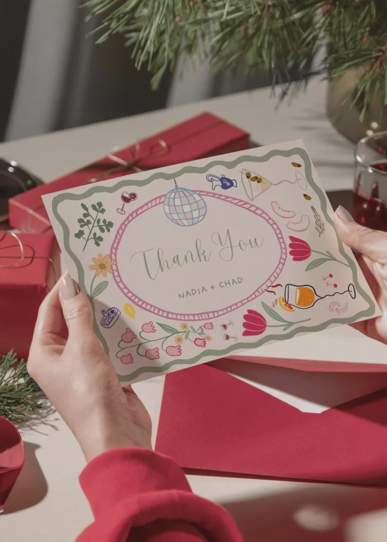 May include: A thank you card with a floral and cocktail-themed design. The card features an oval frame with the words "Thank You" and the names "NADIA + CHAD". The card is held by a person, with a red envelope and gift box in the background.