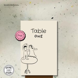 Puede incluir: Una tarjeta de mesa color crema con las palabras "Table ONE" en escritura negra. Una ilustración en blanco y negro de una pareja bailando sobre una pequeña mesa está debajo del texto. La tarjeta tiene una pegatina rosa decorativa que dice "Los colores y el texto se pueden cambiar".