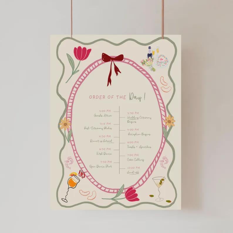 May include: A cream-colored wedding day schedule poster with a pink oval frame and floral illustrations. The text "ORDER OF THE Day!" is at the top, with a detailed timeline of events, including ceremony, dinner, and dance times.