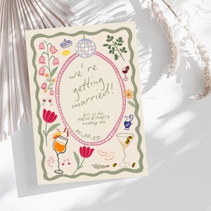 May include: A rectangular wedding invitation card with a cream background, featuring a pink oval frame containing the text 'we're getting married!', 'join us for NADIA & CHAD'S wedding day', and '06.30.25'. The border is decorated with colorful illustrations.