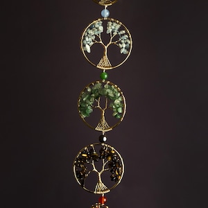 May include: A gold wire tree of life with different colored gemstones hanging from it. The gemstones are arranged in a vertical line and include blue, green, brown, and red.
