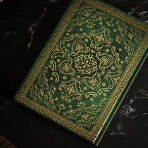 Op de afbeelding: Een groen dagboek met een gouden reli&euml;fpatroon. De omslag heeft een herhalend patroon van sierlijke swirls en bloemmotieven.