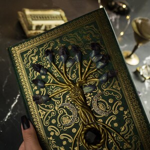 Op de afbeelding: Een groen dagboek met een gouden reli&euml;fdesign met een boom met paarse edelstenen. Het dagboek heeft een donkergroene omslag met een gouden boomontwerp en paarse edelstenen.