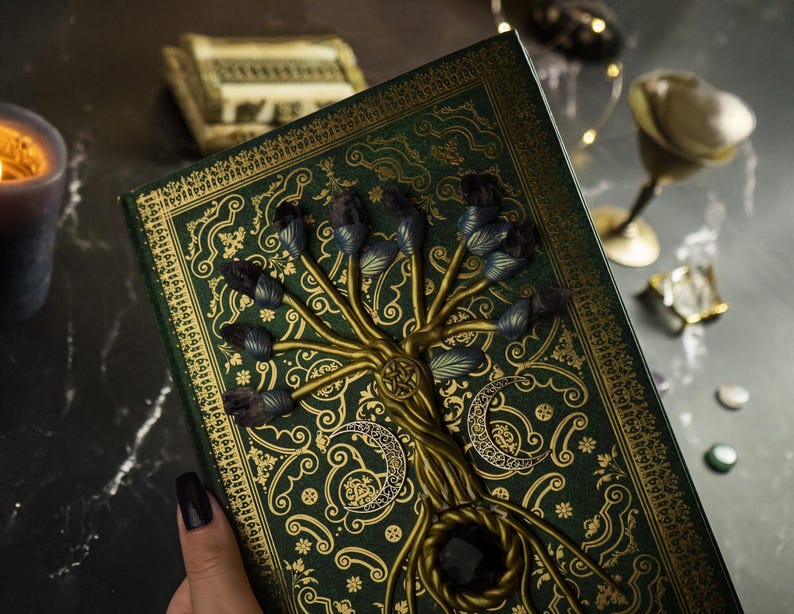 Op de afbeelding: Een groen dagboek met een gouden reli&euml;fdesign met een boom met paarse edelstenen. Het dagboek heeft een donkergroene omslag met een gouden boomontwerp en paarse edelstenen.
