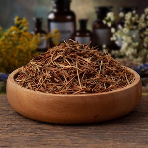 May include: A round wooden bowl filled with a mound of dried, thin, brown herbal twigs and plant stems. The bowl has a smooth, light brown finish and is filled to the brim with the textured, fibrous botanical material, showcasing a natural appearance.