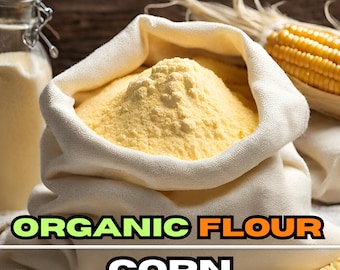 May include: A white cloth bag filled with organic corn flour. The bag is sitting on a wooden surface with a cob of corn in the background. The text "ORGANIC FLOUR CORN" is printed on the front of the bag.