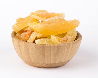 May include: A wooden bowl filled with dried pineapple slices. The pineapple slices are a bright yellow color and have a slightly translucent appearance.