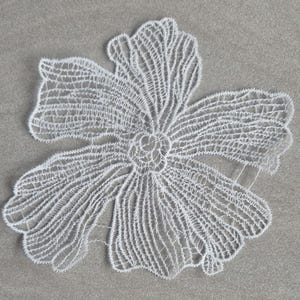 May include: A white lace applique in the shape of a five-petaled flower. The design features intricate, open-work thread patterns that form the delicate structure of the petals and a central circular detail, creating a lightweight, decorative floral motif.