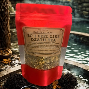 May include: A red pouch of "BC I Feel Like Death Tea" from Apothika 9. The label lists ingredients like lemon balm and green tea. The pouch is partially transparent, revealing the tea leaves. A small bowl of tea leaves sits in front of the pouch.