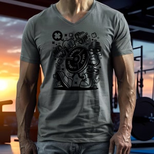 May include: Gray V-neck t-shirt featuring a cartoon barbell character holding dumbbells. The barbell plate reads "BARBELL" and "35 LBS" and "15.9 KILOS". The shirt is a solid gray color.