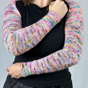 May include: A pair of colorful striped arm warmers made of knitted yarn. The arm warmers are pink, purple, blue, green, and gray.