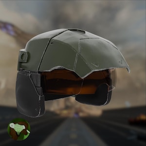 Può includere: Un casco verde e nero con una visiera. Il casco ha una superficie testurizzata e una visiera grigio scuro.