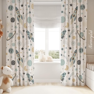 May include: A pair of floor-length curtains featuring a repeating space-themed pattern on a cream background. The design includes illustrations of rockets, planets with rings, stars, moons, and satellites in shades of blue, gray, and yellow.