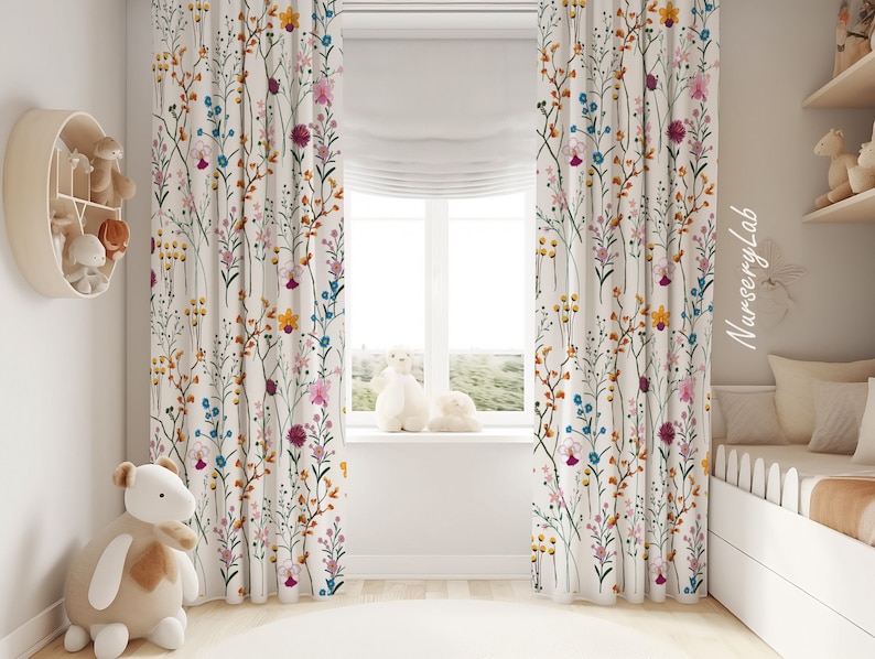 May include: Floor-length curtains featuring a white background with a colorful botanical print of wildflowers in shades of yellow, blue, pink, and purple. The fabric hangs in vertical folds, covering the sides of a window with a white roman shade.
