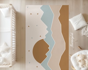 May include: A beige, brown, and blue abstract rug with a sun and mountains design. The rug has a white background with scattered triangles. The text "NurseryLab" is written in white on the right side of the rug.