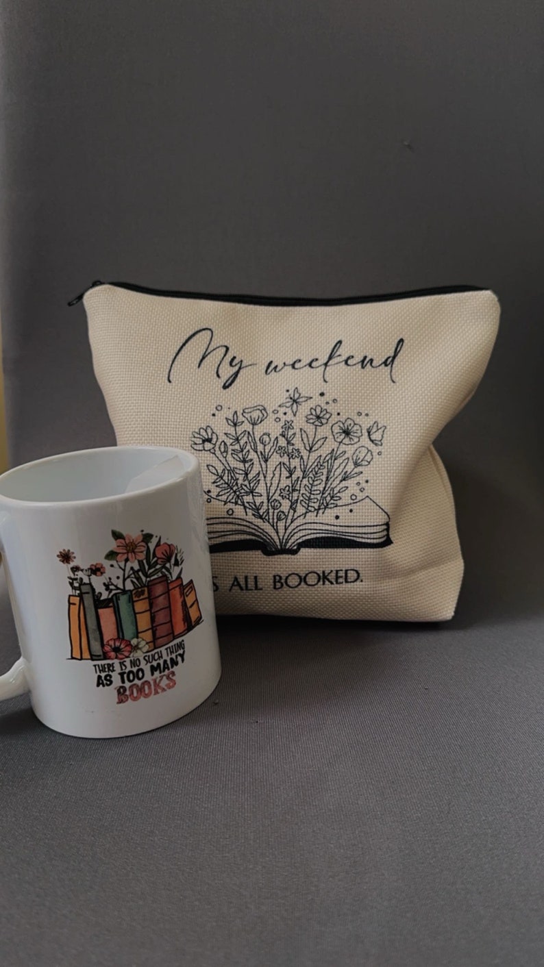 K&ouml;nnte beinhalten: Eine wei&szlig;e Keramiktasse mit einem Blumendesign und dem Text "Es gibt kein solches Ding wie zu viele B&uuml;cher". Eine wei&szlig;e Stofftasche mit dem Text "Mein Wochenende ist ausgebucht" und einem Blumendesign.