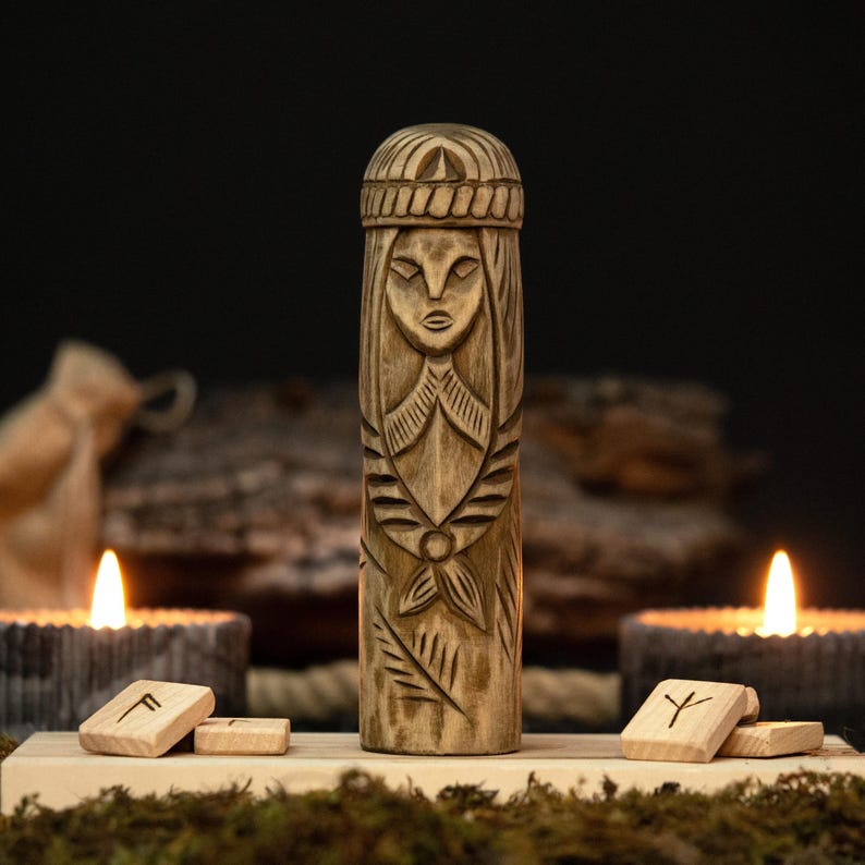 May include: A carved wooden statue of a woman with intricate details, including a headdress and facial features. The statue is displayed on a wooden base with runes and lit candles in the background, creating a mystical ambiance.