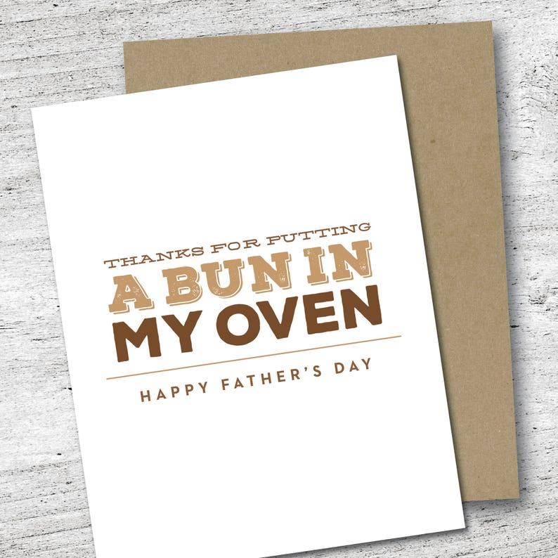 May include: A white Father's Day card with the text "THANKS FOR PUTTING A BUN IN MY OVEN" in brown lettering. The card is paired with a brown envelope. The words "HAPPY FATHER'S DAY" are printed at the bottom.