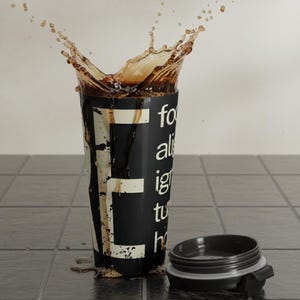 May include: A black travel mug with white text and a splash of liquid. The mug's lid is open and next to the mug. The text on the mug reads "for all ignite the hustle".