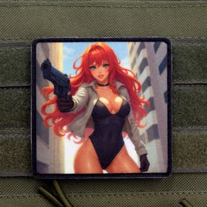 Op de afbeelding: Vierkante patch met een anime-achtige illustratie van een vrouw met rood haar die een pistool vasthoudt. Ze draagt een zwart bodysuit, een witte jas en zwarte handschoenen. De achtergrond toont een stadsgezicht.