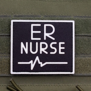 May include: A black and white patch displaying the words "ER NURSE" above a white heartbeat line. The patch has a white border and is set against a green fabric background.