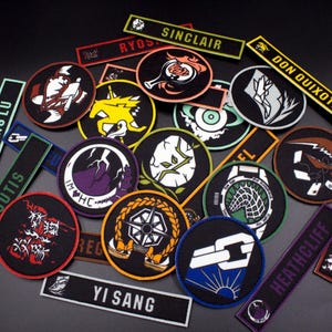 以下が含まれることがあります： 様々なデザインとテキストが施された、丸型と長方形の刺繍パッチ14個のセット。パッチは黒、白、緑、紫、赤、オレンジ、黄、青。パッチのテキストには、「ホン・ルー」、「アウトス」、「イ・サン」、「シンクレア」、「ドン・キホーテ」、「ヒースクリフ」、「ロディオン」、「リョウ」などがあります。