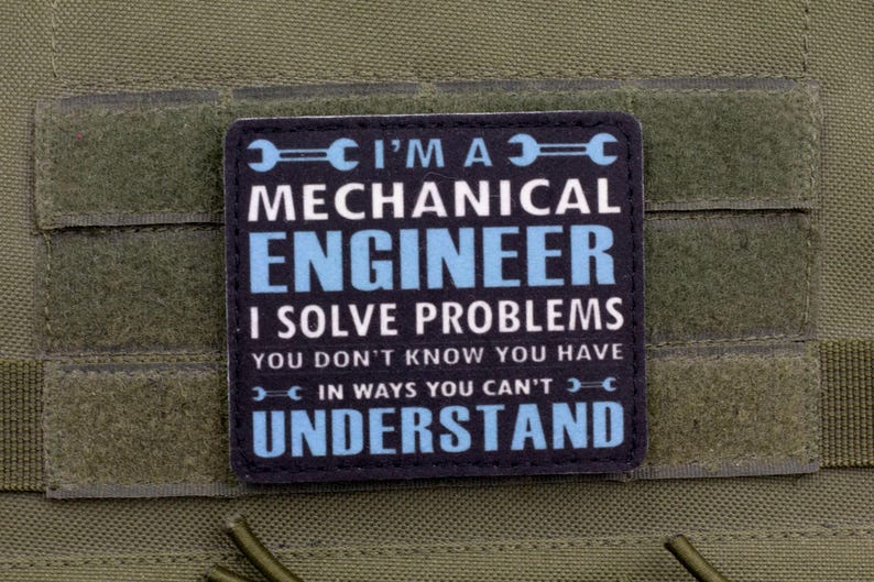 May include: A black and blue patch with the text "I'M A MECHANICAL ENGINEER I SOLVE PROBLEMS YOU DON'T KNOW YOU HAVE IN WAYS YOU CAN'T UNDERSTAND". The patch is on a green fabric.