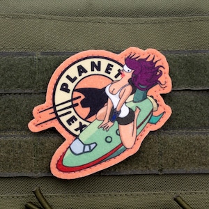 Puede incluir: Un parche bordado rosa y verde con una mujer de dibujos animados montando una nave espacial. La nave espacial tiene las palabras "Planet Express" en el lateral.