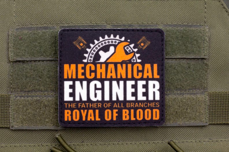 Pu&ograve; includere: Una toppa nera e arancione con le parole "MECHANICAL ENGINEER" in grassetto. La toppa presenta un ingranaggio, una chiave inglese e un pistone. &Egrave; incluso anche il testo "THE FATHER OF ALL BRANCHES ROYAL OF BLOOD".
