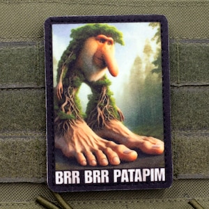 May include: A rectangular patch featuring a whimsical creature with a large nose, tree-like limbs, and large feet. The background shows a forest scene. The text "BRR BRR PATAPIM" is at the bottom.