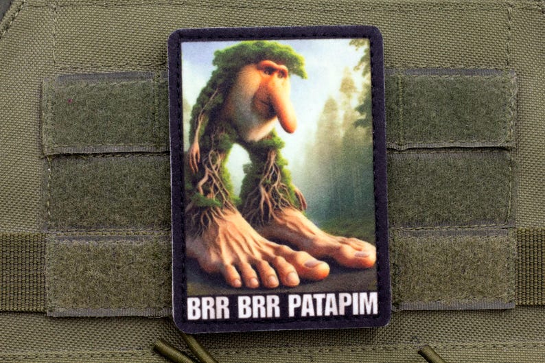 May include: A rectangular patch featuring a whimsical creature with a large nose, tree-like limbs, and large feet. The background shows a forest scene. The text "BRR BRR PATAPIM" is at the bottom.