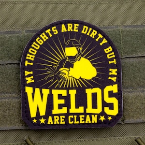 May include: A black and yellow patch with the text "MY THOUGHTS ARE DIRTY BUT MY WELDS ARE CLEAN" and an illustration of a welder. The patch is attached to a green tactical vest.