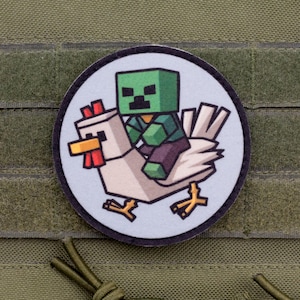 Puede incluir: Un parche redondo con un personaje verde pixelado montado en un pollo blanco. El personaje tiene una cabeza cuadrada verde y lleva una camisa y pantalones marrones. El pollo tiene una cresta roja y un pico amarillo. El parche está sobre un fondo verde.